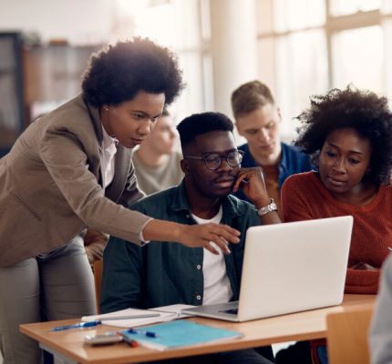 African American professor and her students using laptop during lecture in the classroom.